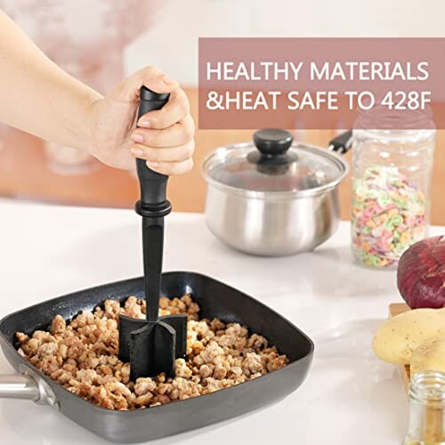 Using a meat masher on cooked ingredients in a pan.