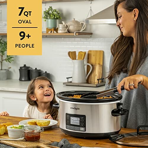 Woman serving food from a slow cooker to a smiling child in a kitchen.